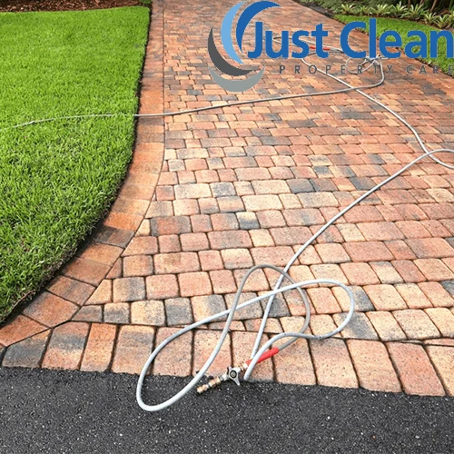 Curving block-paved garden path with a hose laid beside it