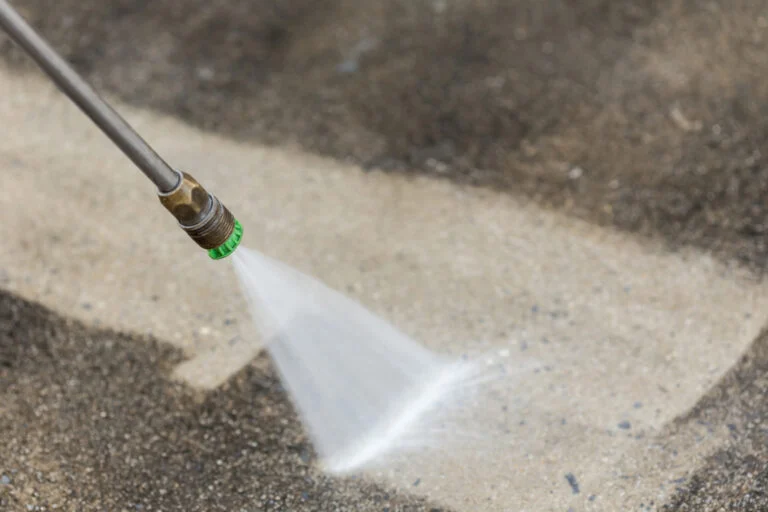 Worker pressure washing an exterior paved area