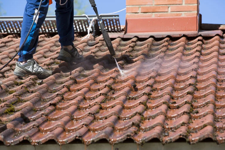 Worker washing a tiled roof
