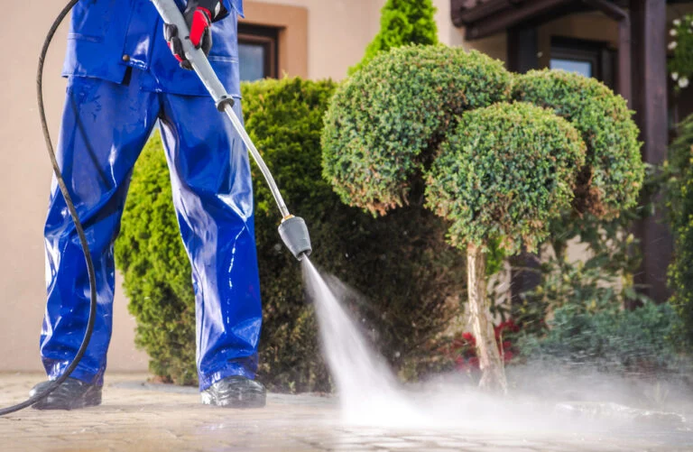 Worker pressure washing an exterior paved area