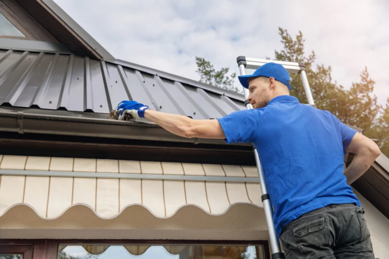 Worker washing a roof with a long-reach cleaning pole