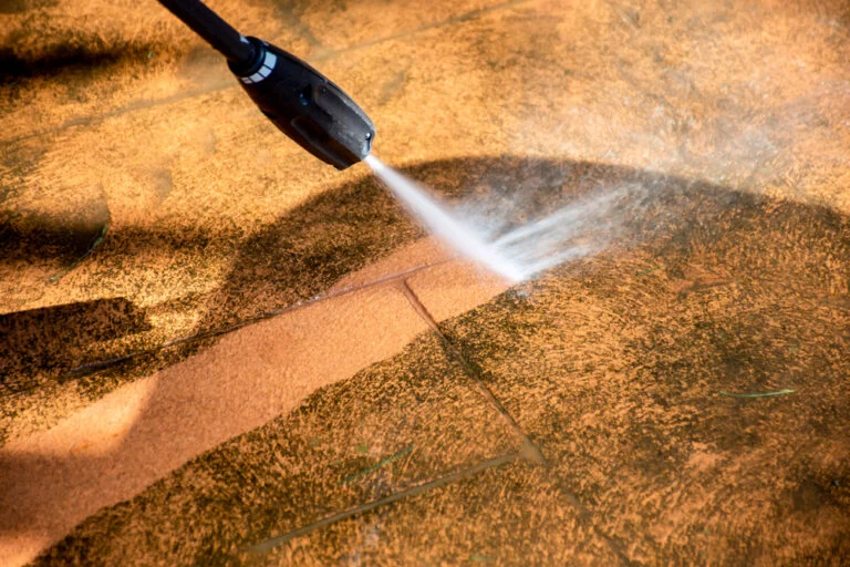 Worker pressure washing an exterior paved area