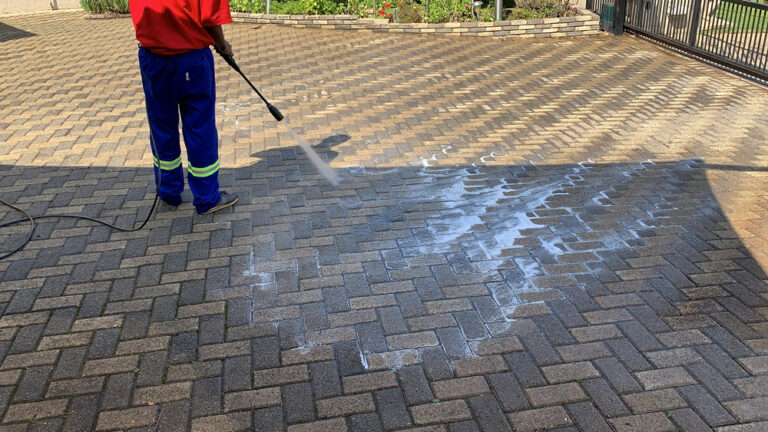 Worker pressure washing an exterior paved area