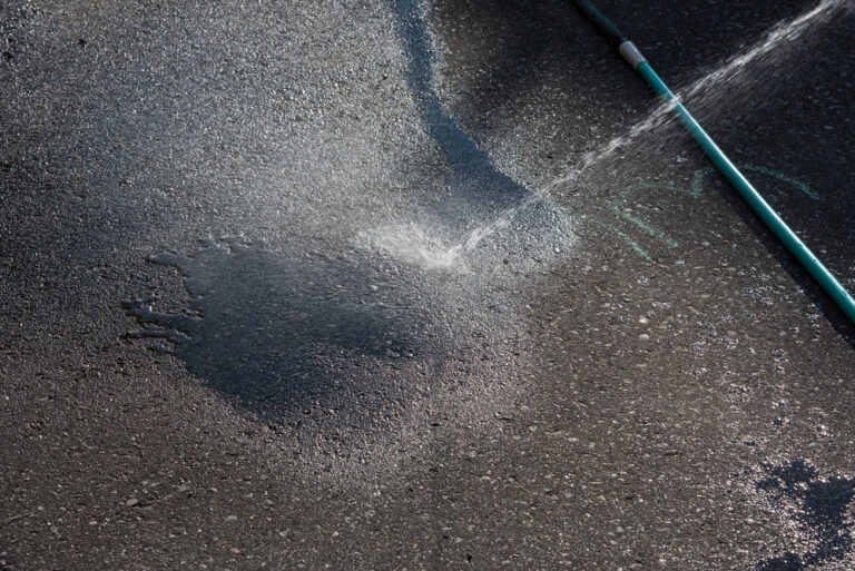 Worker pressure washing an exterior paved area