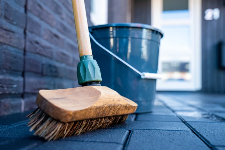 Scrubbing a paved surface with a stiff brush