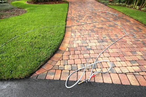 Curving block-paved garden path with a hose laid beside it