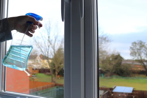 Cleaning a white window frame with a spray bottle