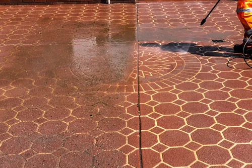 Worker pressure washing an exterior paved area