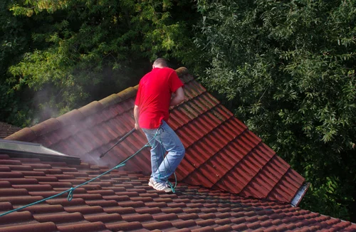 Worker washing a red tiled roof
