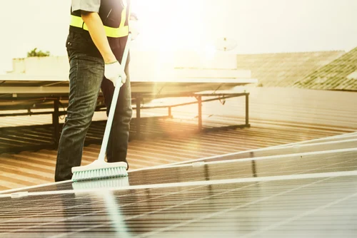 Worker brushing water across an exterior timber deck