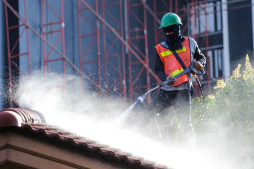Worker using a washing lance on the outside of a building