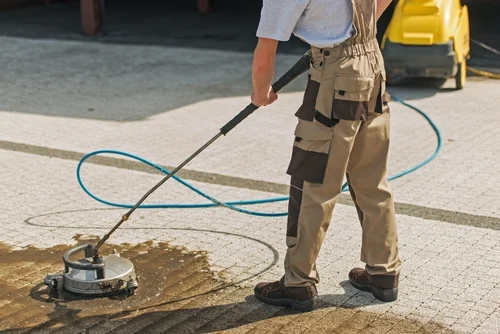Worker using a surface cleaner on paving