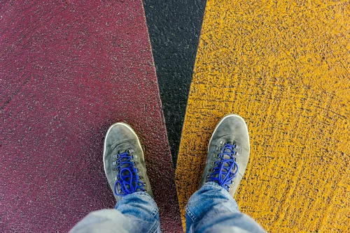 Feet on two differently coloured paving surfaces