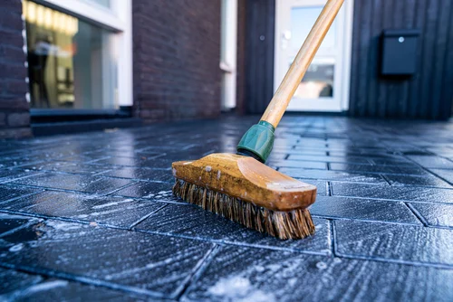 Scrubbing a paved surface with a stiff brush