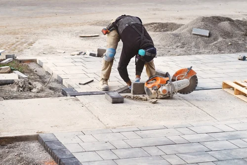 Worker laying paving on a driveway