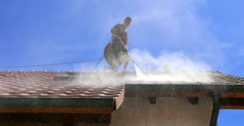 Cleaning a red tiled roof with a washing lance