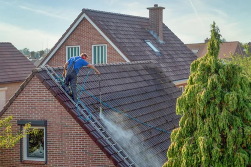 Cleaning a red tiled roof with a washing lance