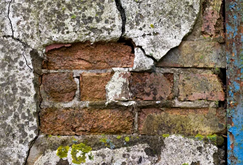 Damaged render exposing brickwork