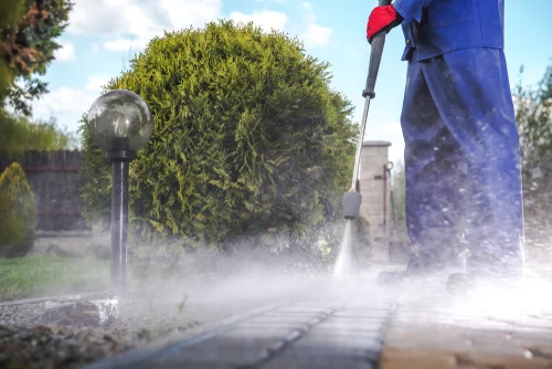 Pressure washing a driveway beside a house