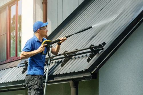 Worker washing a roof with a long-reach cleaning pole