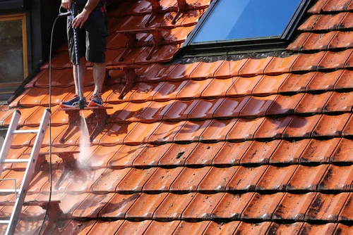 Cleaning a red tiled roof with a washing lance