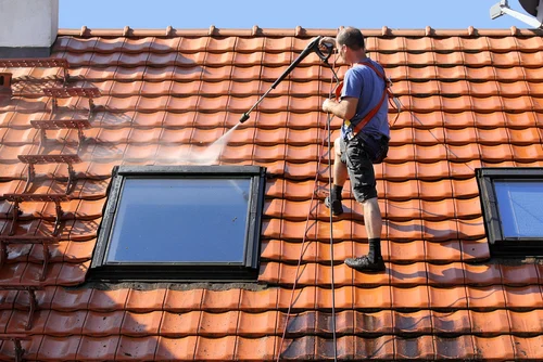 Worker washing a tiled roof