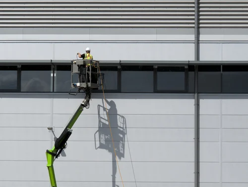 Worker washing exterior wall cladding