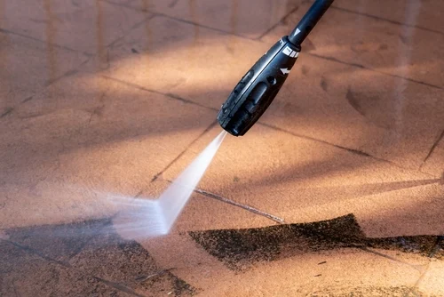 Worker pressure washing an exterior paved area