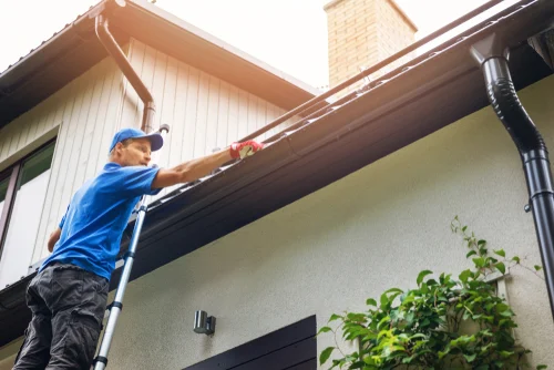 Worker cleaning the outside of a roof gutter