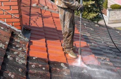 Cleaning a red tiled roof with a washing lance