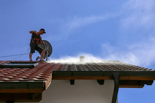 Cleaning a red tiled roof with a washing lance