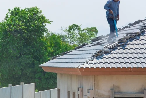 Worker washing a tiled roof