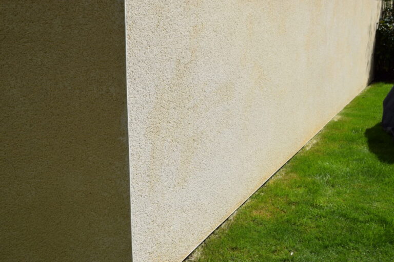 Light-coloured rendered wall beside a lawn