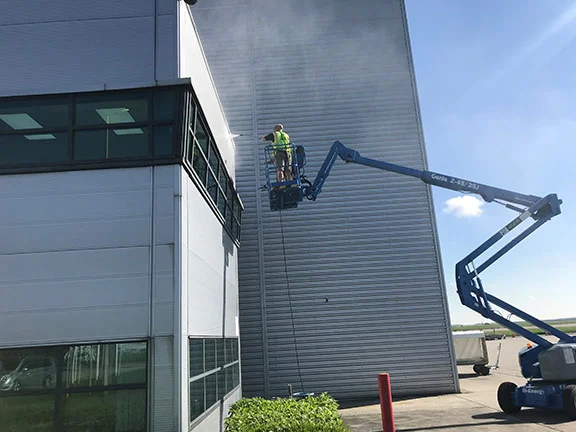 Worker washing exterior wall cladding