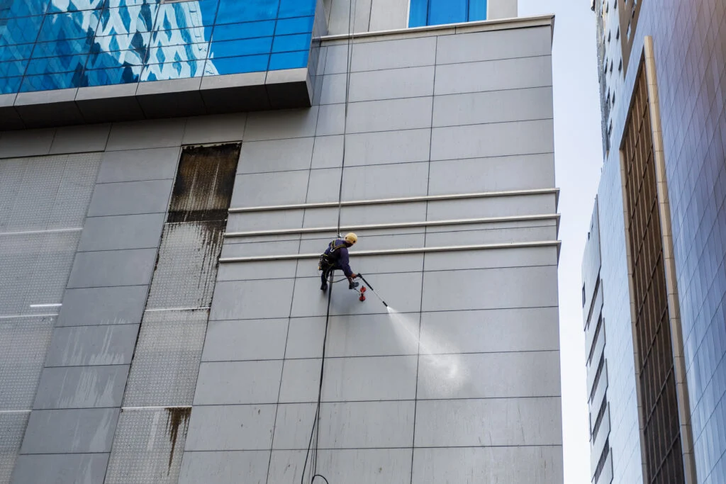 Worker washing exterior wall cladding
